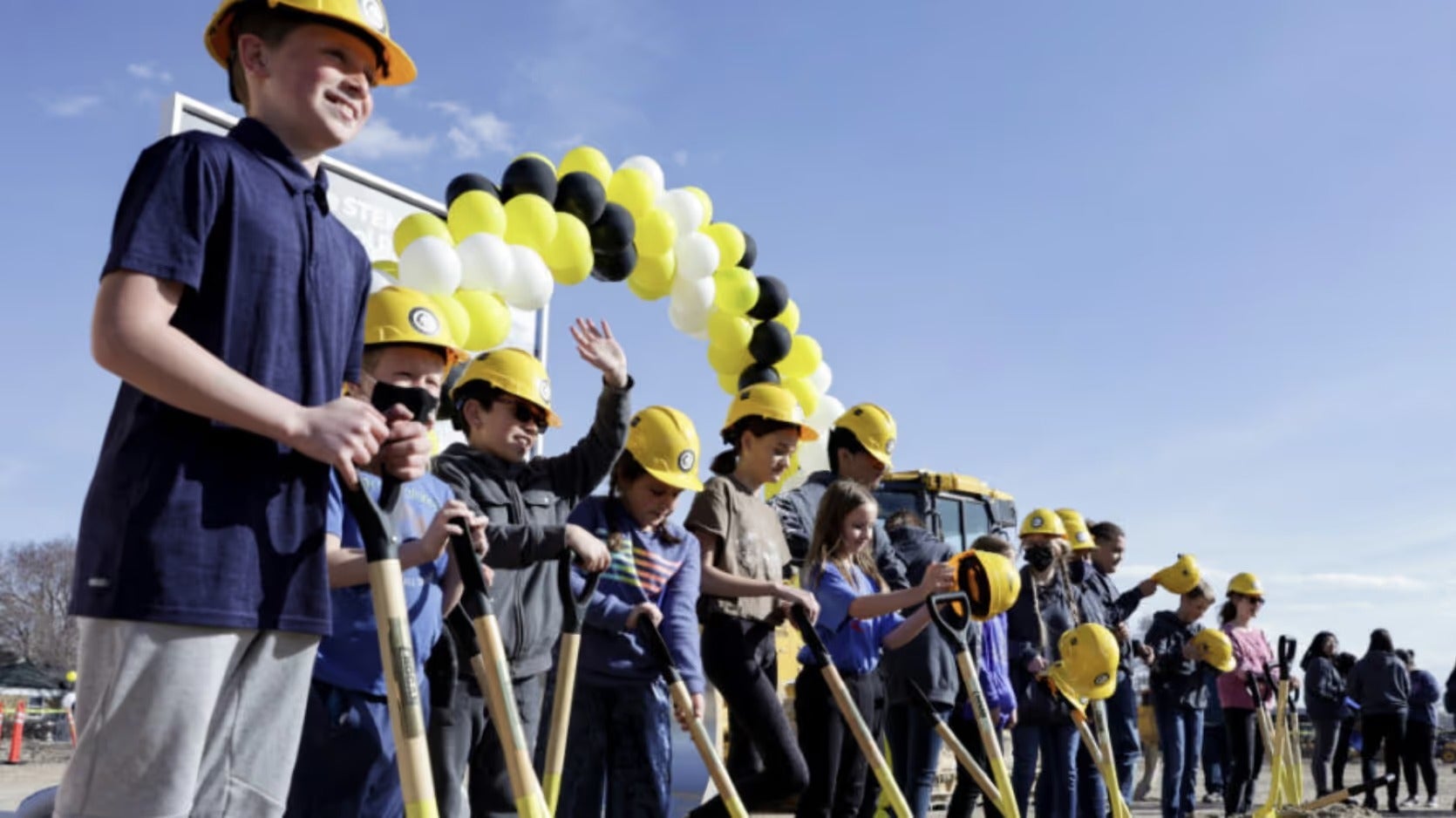 Students in yellow hard hats hold shovels at a West Lake STEM groundbreaking ceremony
