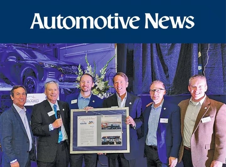 Mark Miller and Subaru of America executives holding a framed 50-year award