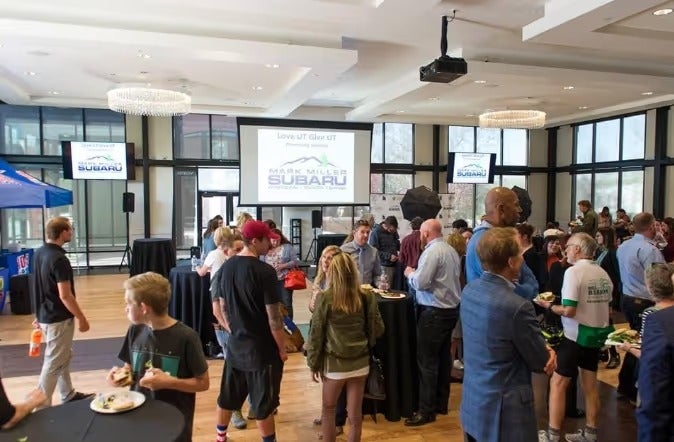 Crowded indoor community event with a Mark Miller Subaru banner