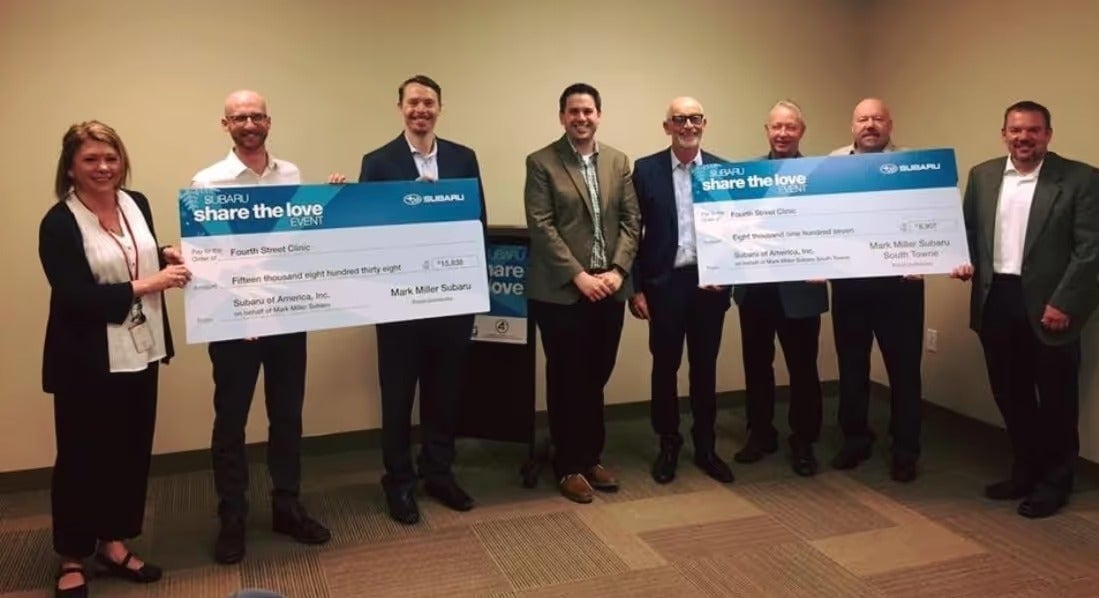 Group holding oversized Share the Love donation checks indoors