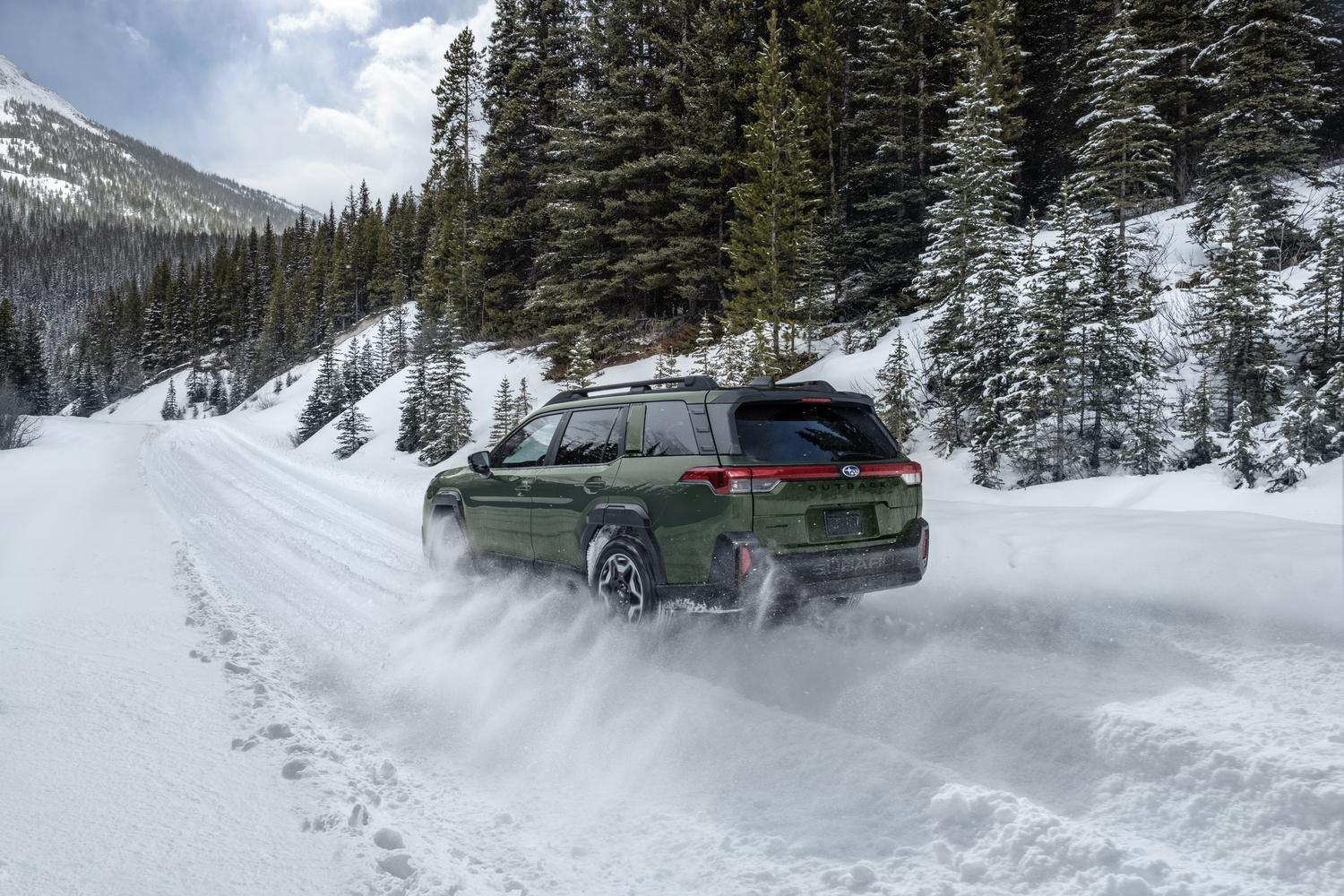 2026 Subaru Outback throwing snow on a forest road, rear three-quarter view
