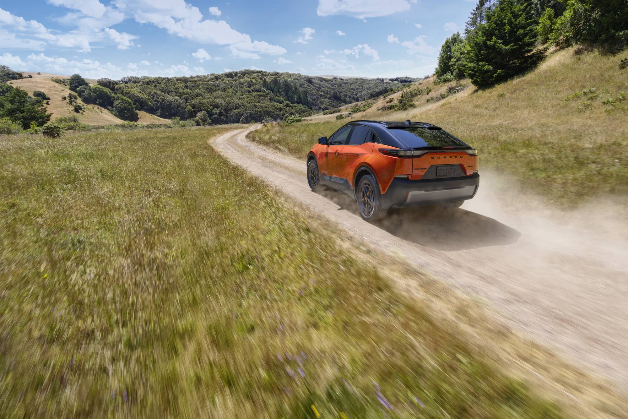 2026 Subaru Uncharted in Habanero Orange on a dirt road through golden hills